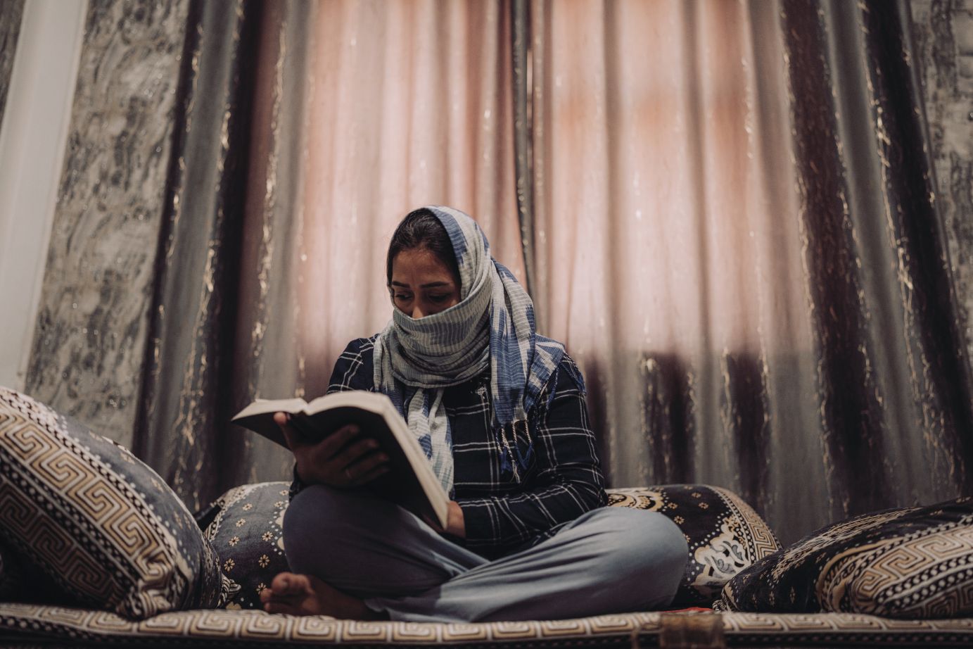 Una mujer con un pañuelo está leyendo la Biblia.